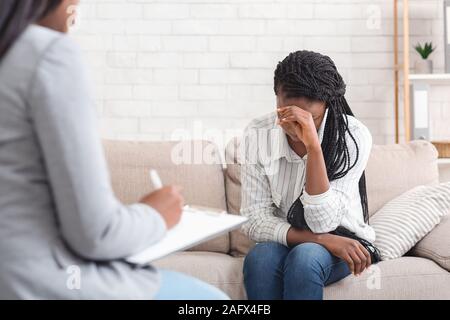 Premuto donna seduta sul lettino a psicoterapia sessione in coucellor dell'ufficio Foto Stock