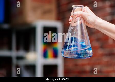 Farmacia tenendo un pallone di liquido di colore blu in mano Foto Stock