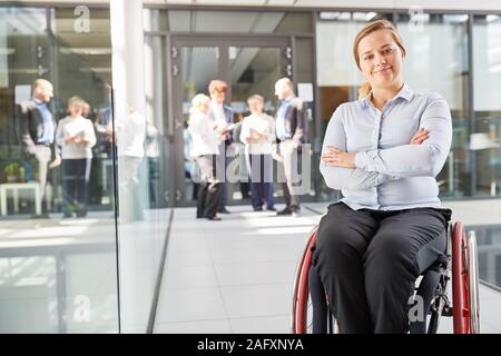 Young business woman in una sedia a rotelle con bracci incrociati per inclusione di business Foto Stock