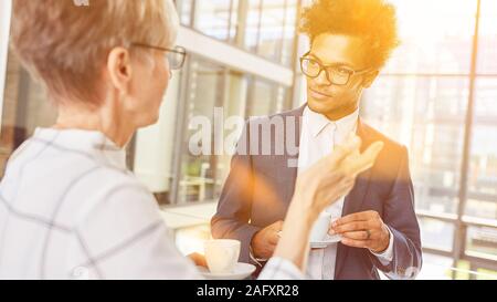 Due persone di affari a parlare tra di loro in ufficio in un caffè Foto Stock