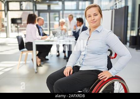 Orgogliosa imprenditrice in una sedia a rotelle nella parte anteriore del suo team in un seminario o una riunione Foto Stock