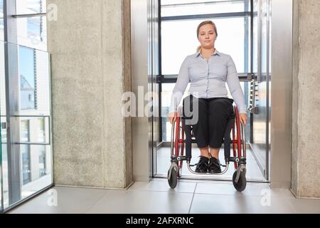 Imprenditrice come una sedia a rotelle in ascensore nella barriera di società libera sulla strada Foto Stock