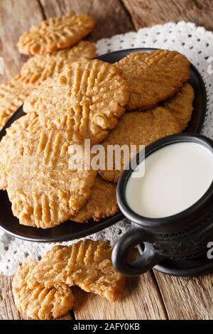 Appena sfornato il burro di arachidi cookie con un bicchiere di latte vicino sul piano verticale. Foto Stock