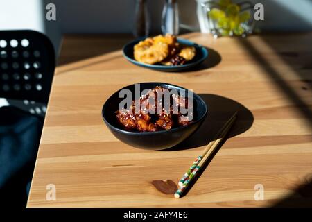 Cibo asiatico in Casa Generale Cinese Tso pollo con i semi di sesamo servito con bacchette. I cibi tradizionali. Foto Stock