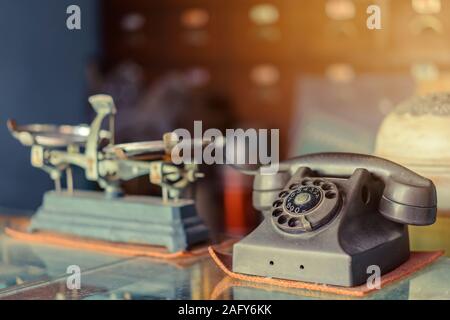 Il vecchio telefono nero con manopola con polvere e graffi collocato su un vetro trasparente armadio in una antica farmacia. Foto Stock