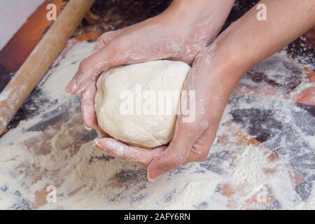 Donna preparazione impasto di farina. Mani femminili tenendo in mano un pezzo di pasta cruda. Foto Stock