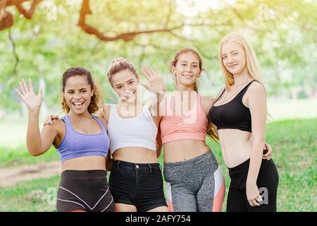 Gruppo di sano sport donne amico insieme hi cinque saluto a mano guardando la telecamera per esterni al parco verde per la riunione insieme di allenamento. Foto Stock