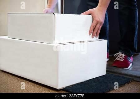 L'uomo la ricezione di scatole / pacchetti nella parte anteriore della porta. Foto Stock