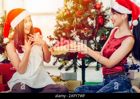 Donna asiatica Natale dando nuovo anno confezione regalo presenti al suo amico sensazione di espressione di sorpresa. Foto Stock