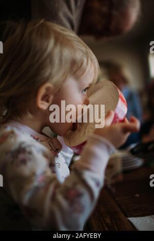 Bambino che lambisce la parte superiore del contenitore per gelato Foto Stock