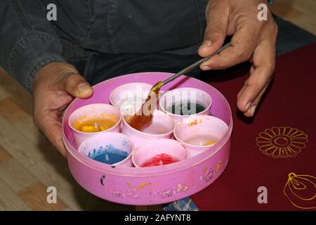 Rogan arte praticata nel distretto di Kutch del Gujarat, India. Vernice realizzata da olio di ricino e tinture vegetali è applicata al tessuto utilizzando una stilo Foto Stock