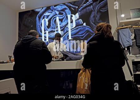 Ai clienti che pagano per gli acquisti e il giovane uomo che lavora presso la cassa in GAP negozio di abbigliamento in Londra England Regno Unito KATHY DEWITT Foto Stock