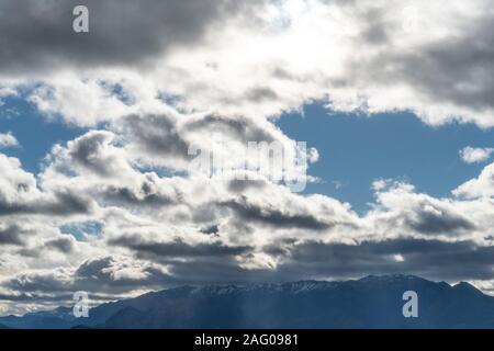 Colorate nuvole di contrasto su un luminoso cielo blu sopra le cime delle montagne. Splendido sfondo del paesaggio Foto Stock