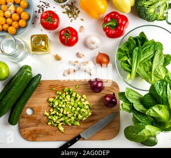 Fette di avocado su una tavola di legno e diversi ortaggi sul tavolo. Ingredienti per insalata. Una dieta salutare concetto. Vista dall'alto. Foto Stock