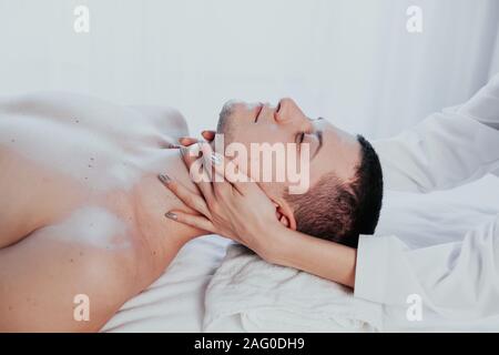 Medico cosmetologo facendo il massaggio del viso uomini trattamenti termali Foto Stock