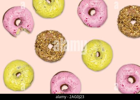 Ciambelle multicolore che cade contro il sfondo rosa. Foto Stock