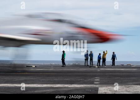 Stati Uniti I marinai della marina di guardare un T-45C Astore formazione aeromobili jet assegnati alla formazione Air Wing 2 atterrare sul ponte di volo della portaerei USS John C. Stennis Dicembre 9, 2019 nell'Oceano Atlantico. Foto Stock