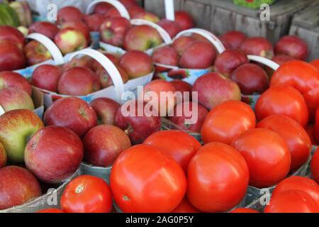 Dei pomodori e delle mele in cesti con maniglie Foto Stock