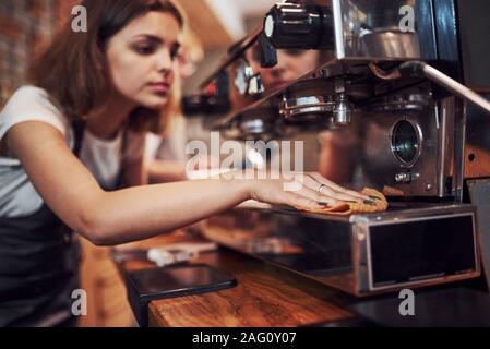 Ragazza pulisce la macchina. Femmina e giovane lavoratore cafe all'interno. Concezione di business e del servizio Foto Stock