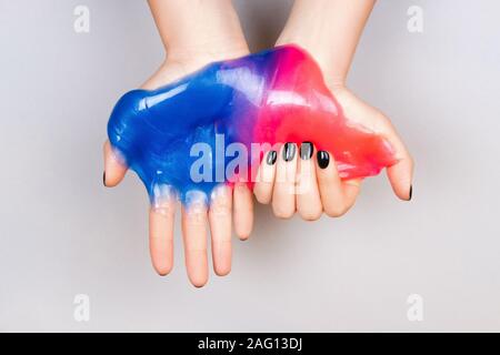 Mani con manicure nero tenendo il fango in blu e rosa colori vibranti Foto Stock