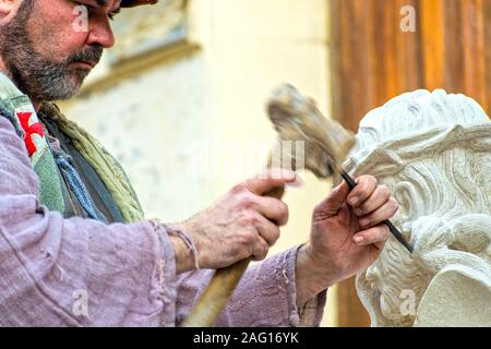 Caravaca de la Cruz, Spagna, Dicembre 10, 2019: scultore della pietra che intaglia un Cristo con la corona di spine. Professional artigiano, un artista uomo di lavoro Foto Stock