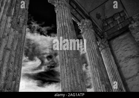 Antica architettura romana e archeologia in Assisi. Tempio di Minerva vecchie colonne con le nuvole, eretto nel I secolo A.C. (bianco e nero) Foto Stock