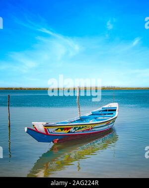 Tradizionale in legno colorato barca sul fiume in mare laguna e un bellissimo cielo in background, Africa Senegal. Si tratta di una giornata di sole. Foto Stock