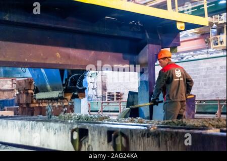 Lavoratore opera la macchina sulla realizzazione di piastre Foto Stock