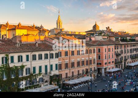 La luce solare colpisce le torri e tetti oltre la Piazza Navona come turisti godere presto la sera al tramonto a Roma, Italia. Foto Stock