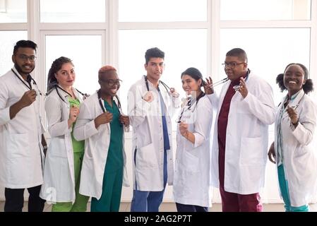 Gli studenti di medicina, medici, razza mista. Un team di giovani in camici in posa nel corridoio dell'ospedale Foto Stock