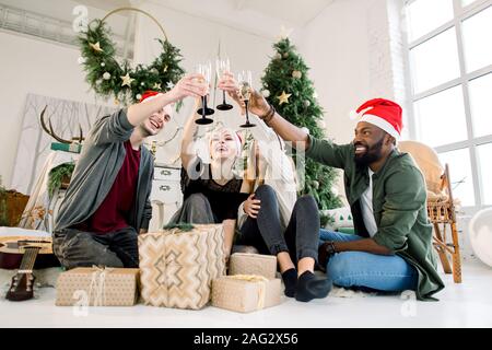 Gruppo di amici per celebrare il Natale a casa e cappucci di tostare con champagne, di Natale o Capodanno concetto. Foto Stock