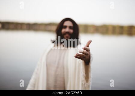 Gesù Cristo presta una mano d'aiuto con uno sfondo sfocato Foto Stock