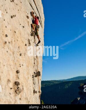 A basso angolo di visione del rocciatore salendo sulla verticale lato montagna. Foto Stock