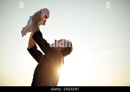Molto felice uomo maturo sollevando la sua bimba in aria. Foto Stock