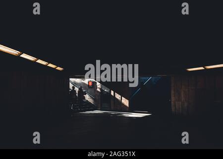 Silhoette di due persone che entrano in un edificio sotterraneo oscuro ombreggiato Foto Stock