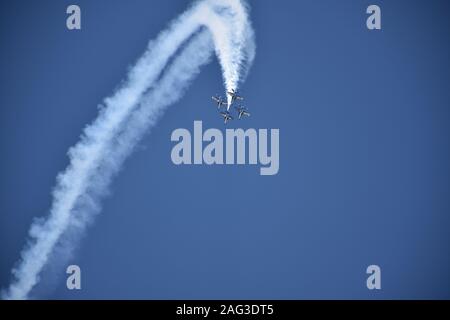 Inquadratura a basso angolo di quattro aerei che volano con manovre lasciando un enorme sentiero bianco nel cielo Foto Stock