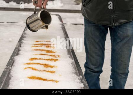 Sciroppo di acero viene versata su ghiaccio fresco per effettuare una tradizionale capanna di zucchero dessert in Quebec, Canada. Foto Stock