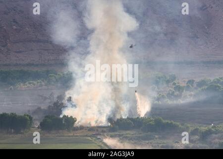 Un elicottero gocce acqua a combattere un incendio brucia in Nature Conservancy Scott M. Matheson Zone Umide riserva vicino Moab Utah. Foto Stock