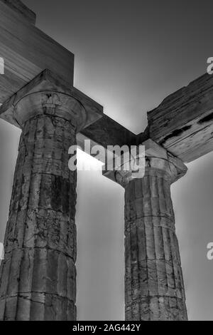 Scala di grigi verticale a basso angolo di colonne di un antico edificio storico sotto il bel cielo Foto Stock