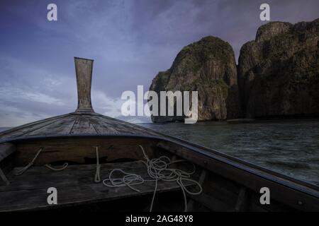 Bellissimo scatto di una barca di legno isolata su una calma mare vicino alle scogliere sotto il cielo mozzafiato Foto Stock