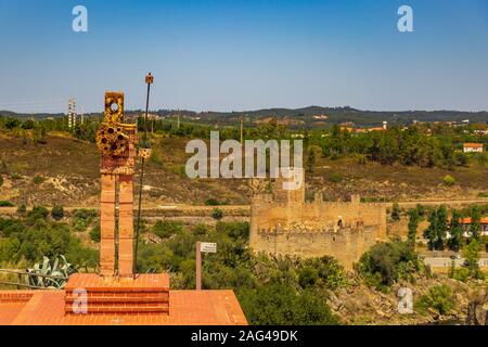 Bellissimo scatto di una scultura moderna su un piedistallo in pietra di fronte a colline e una piccola fortezza Foto Stock