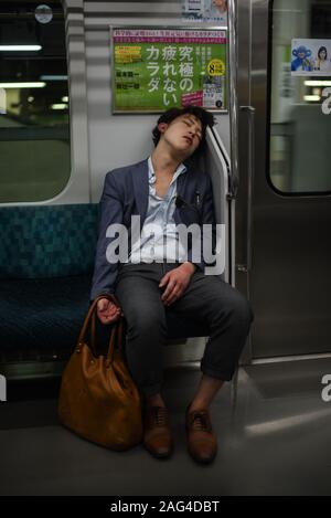 Giovane uomo dorme nella metropolitana Tokyo, Giappone Foto Stock