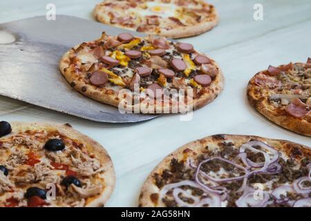 Serve una serie di diversi mini pizza sul tavolo di legno. Pizzette Foto Stock