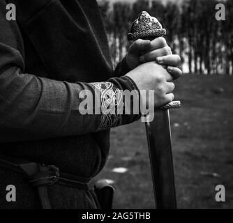 Immagine in scala di grigi di un guerriero che indossa abiti tradizionali nazionali una spada Foto Stock