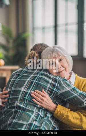 Amare la mamma. Grey-haired anziana signora sentirsi felice con suo figlio Foto Stock
