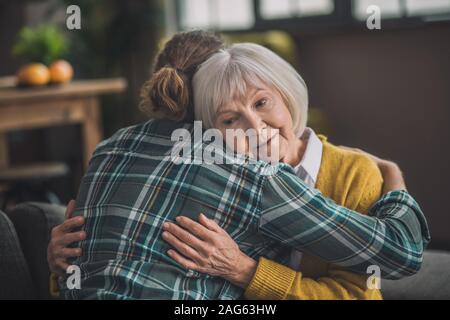 Abbracci. Grey-haired anziana signora cercando felice con suo figlio Foto Stock