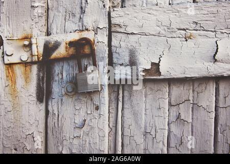 Lucchetto arrugginito appeso su un antico cancello di legno bianco - ideale per uno sfondo o uno sfondo Foto Stock