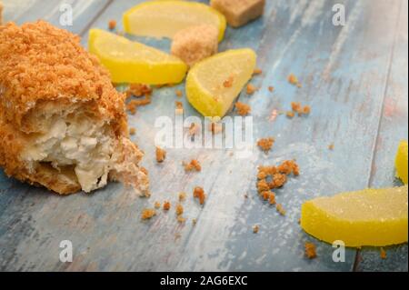 Uno rotto torta, pezzi di zucchero di canna e marmellata fette di limone su un sfondo di legno Foto Stock