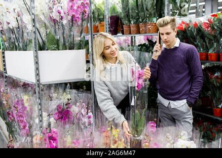 Piuttosto giovane picks orchidee nel negozio. Scelta di fiori in un negozio di fiori Foto Stock