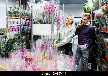 Piuttosto giovane picks orchidee nel negozio. Scelta di fiori in un negozio di fiori Foto Stock